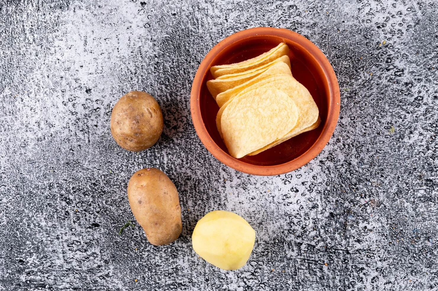 top-view-chips-bowl-with-fresh-potatoes-white-stone-horizontal_176474-1184